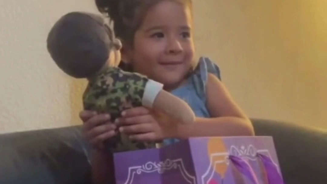 Child smiling and holding plush doll on couch  




